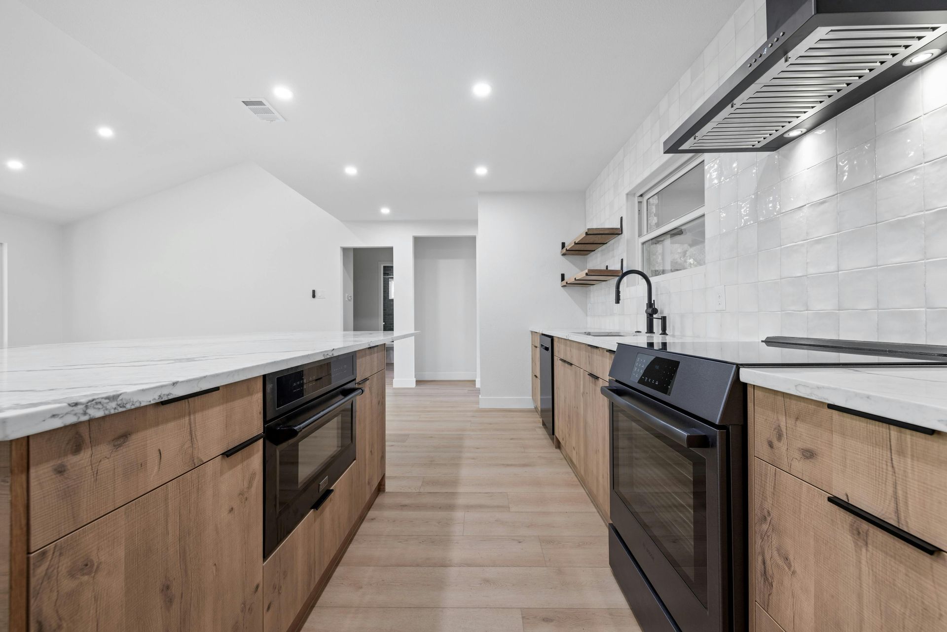 A kitchen with wooden cabinets , black appliances , and white counter tops.