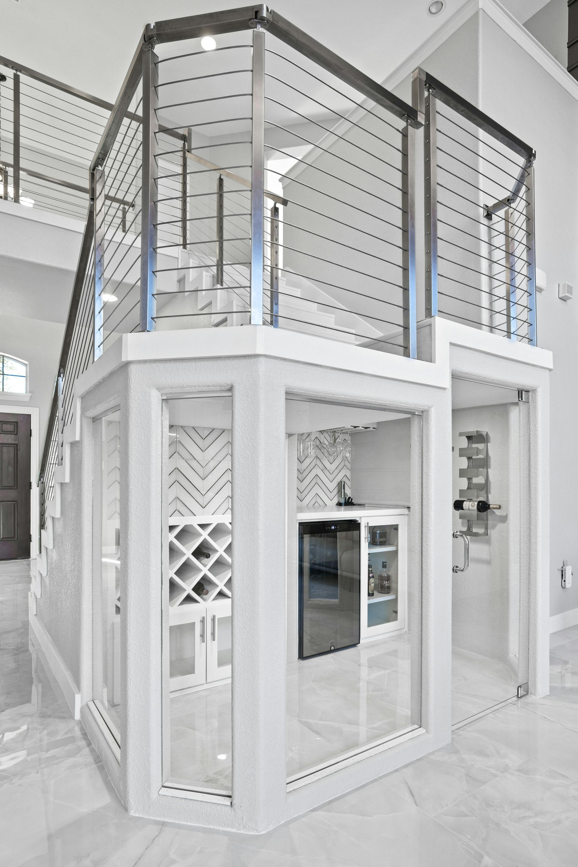 A white room with a staircase and a wine cellar underneath it.