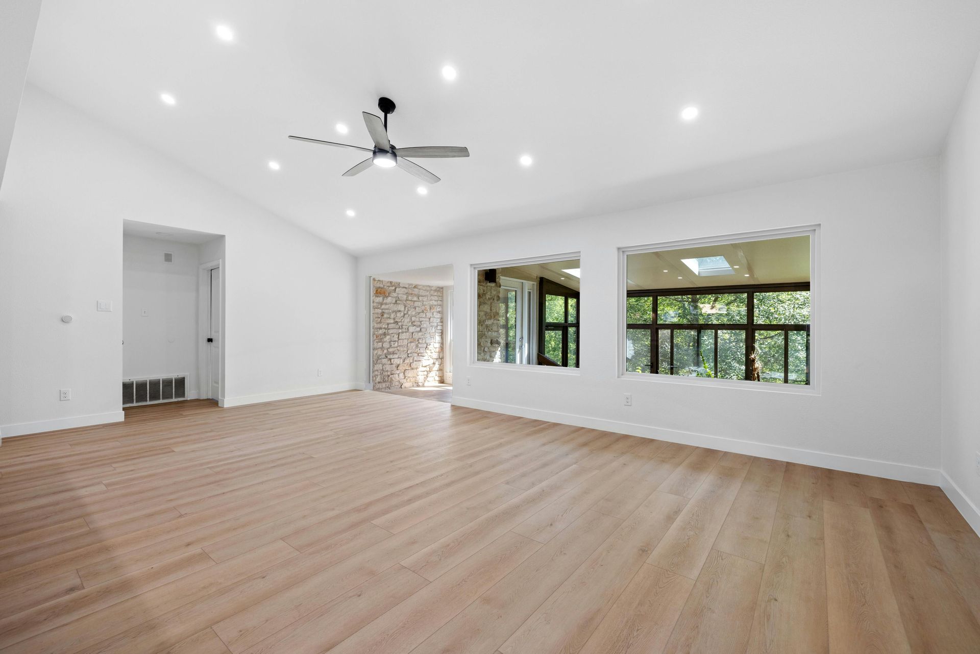 An empty living room with hardwood floors and a ceiling fan.