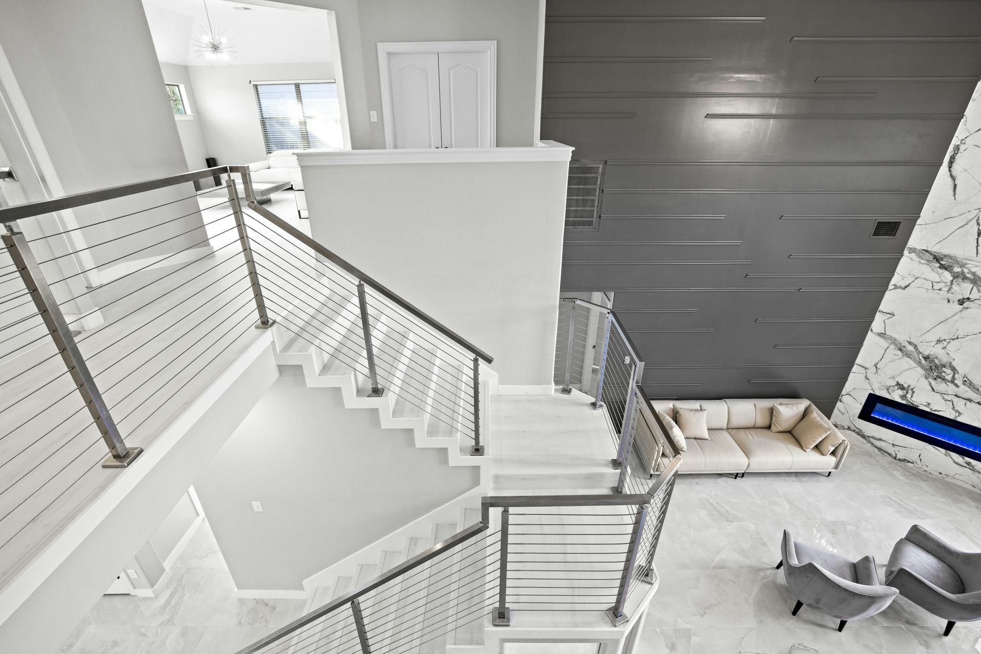 An aerial view of a staircase in a living room with a couch and chairs.