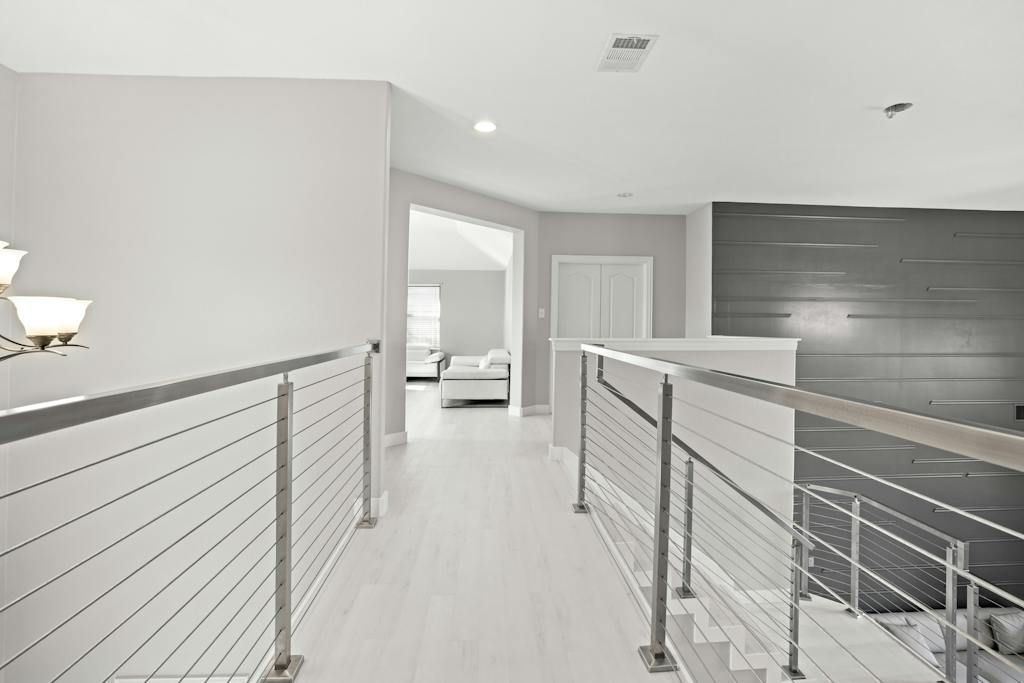 A hallway with a stainless steel railing and stairs