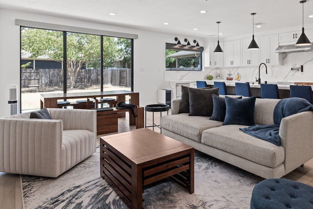 A living room with a couch , chair , coffee table and rug.