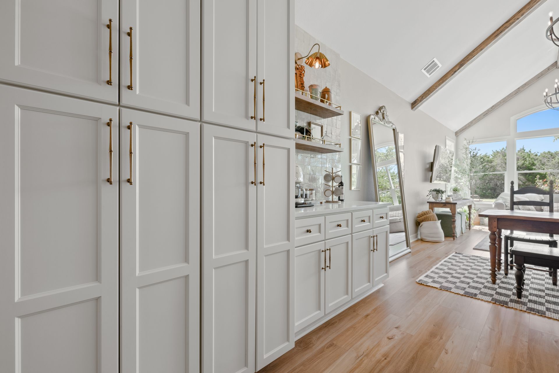 A kitchen with white cabinets , wooden floors , a table and chairs.