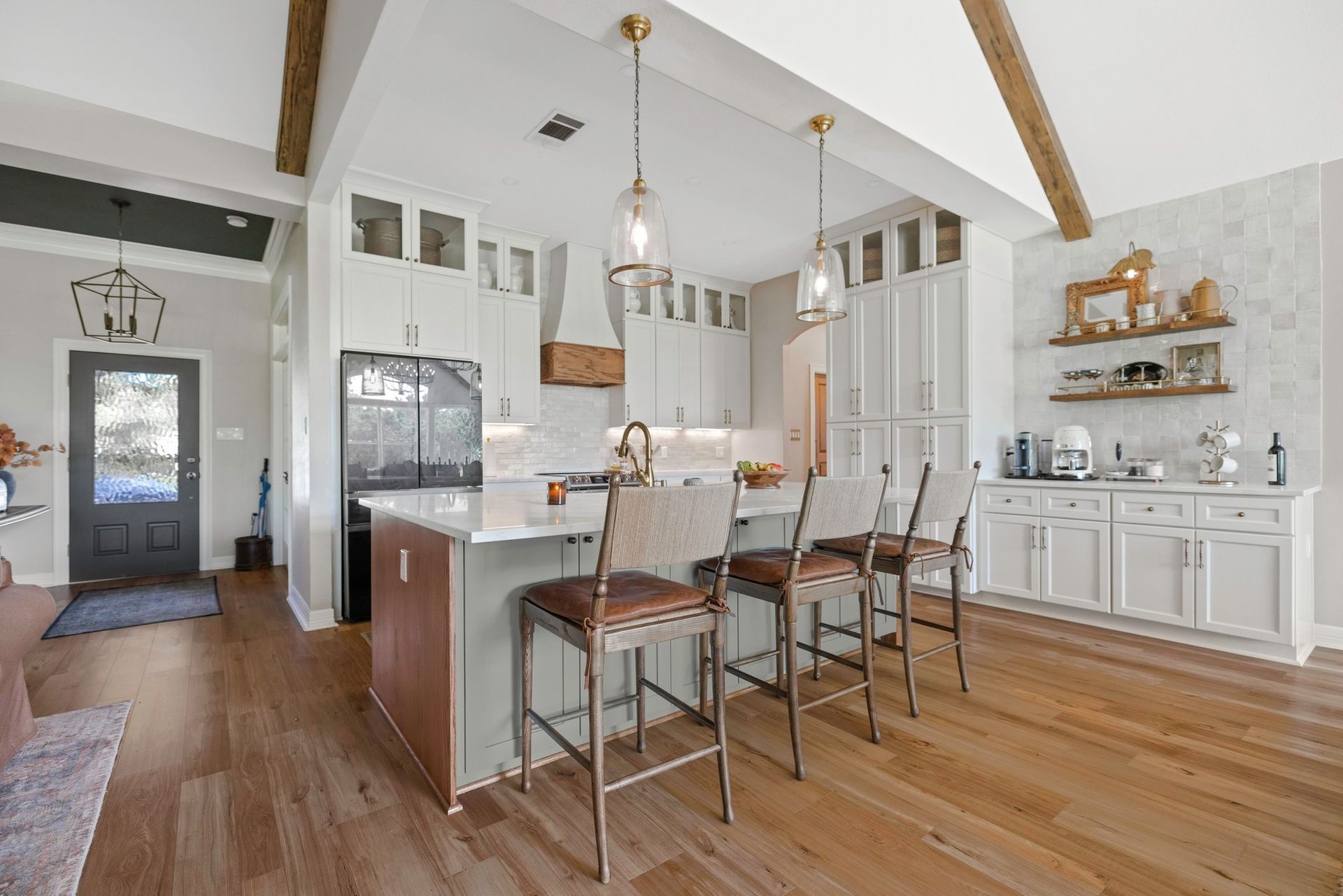 A kitchen with a large island and stools in a house.