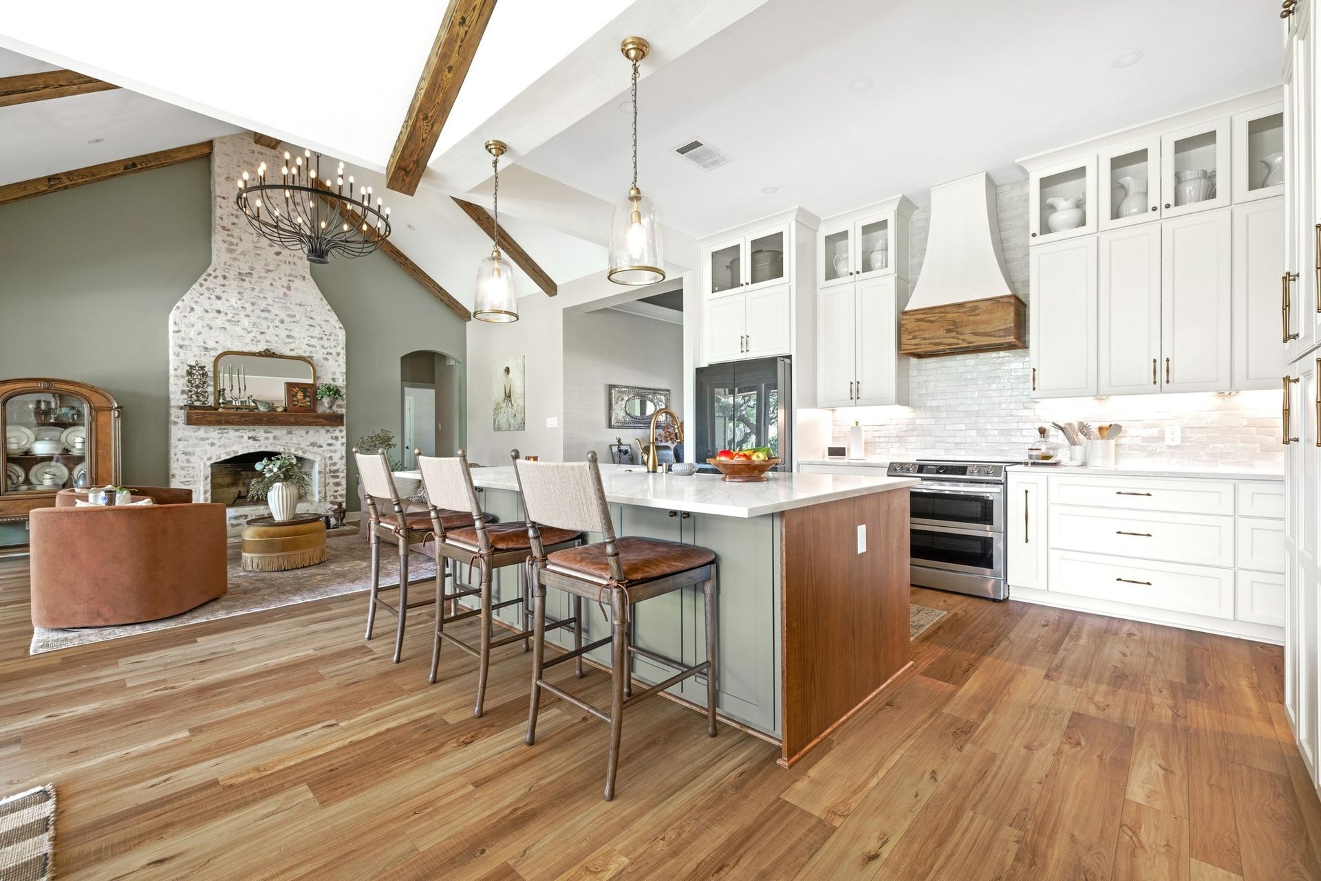A kitchen with white cabinets and wooden floors and a large island.