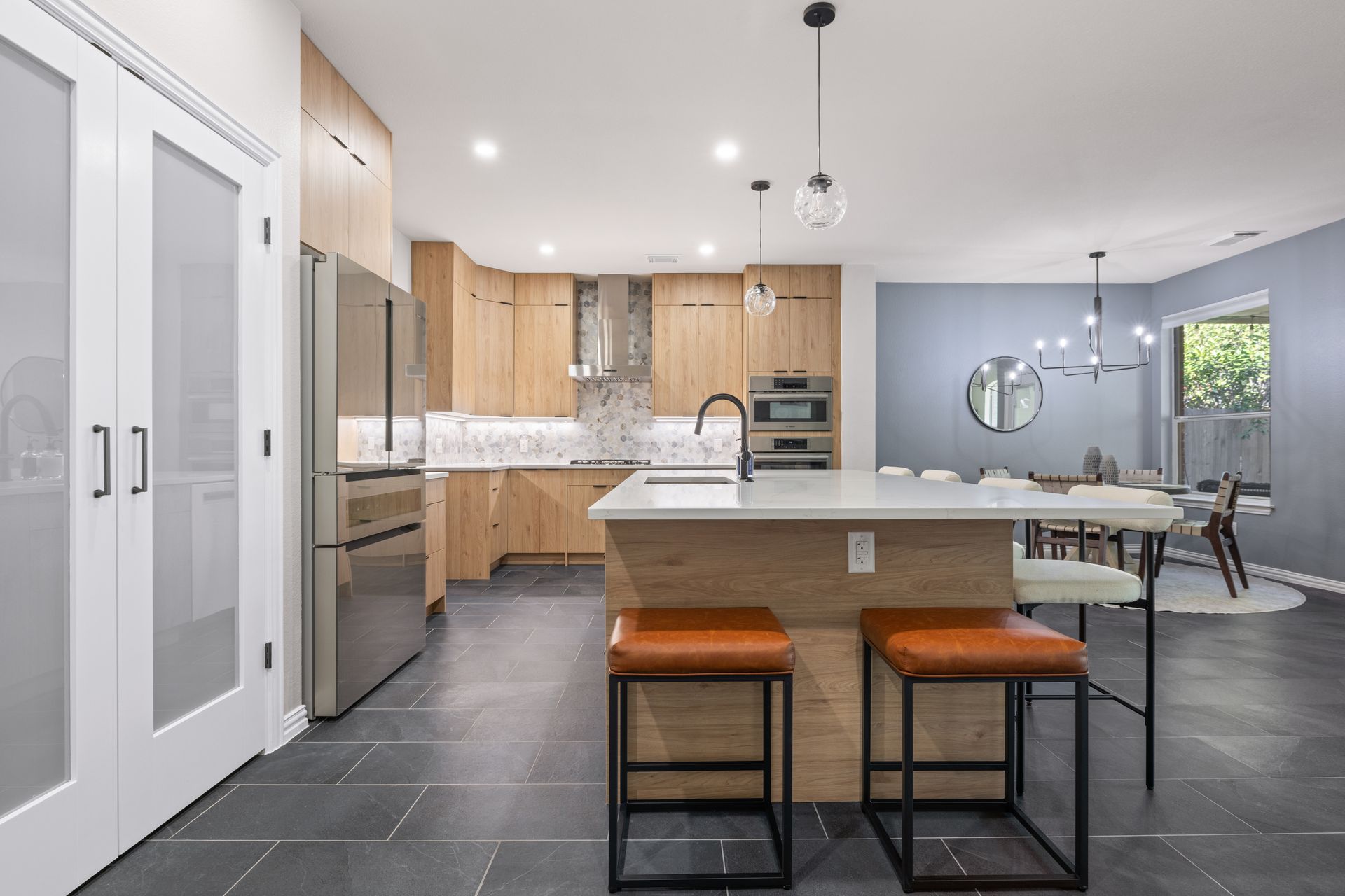 Open-concept kitchen and dining area with modern finishes, wood cabinets, and a functional island centerpiece