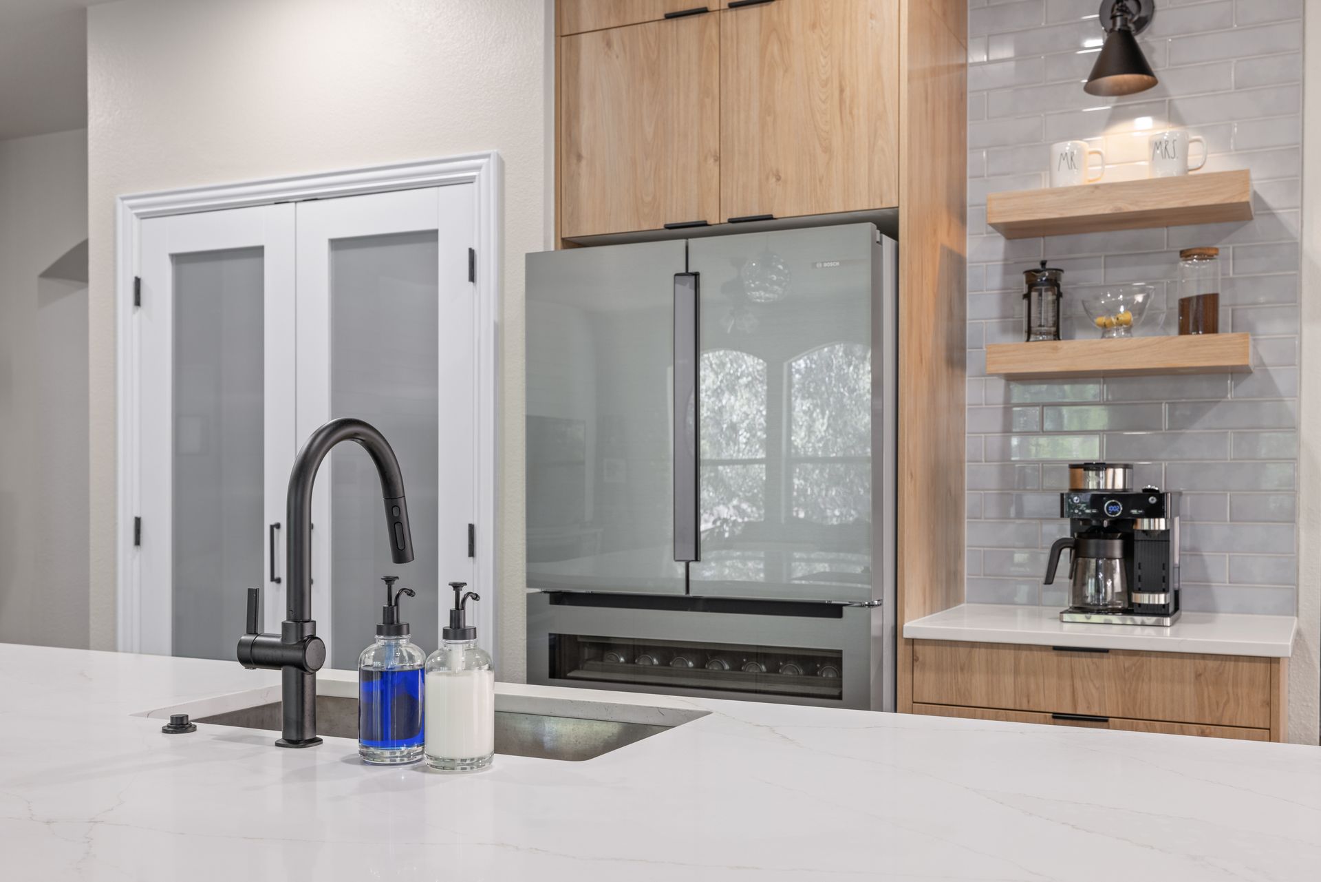 Large island, counter depth refrigerator, and pantry doors with frosted glass