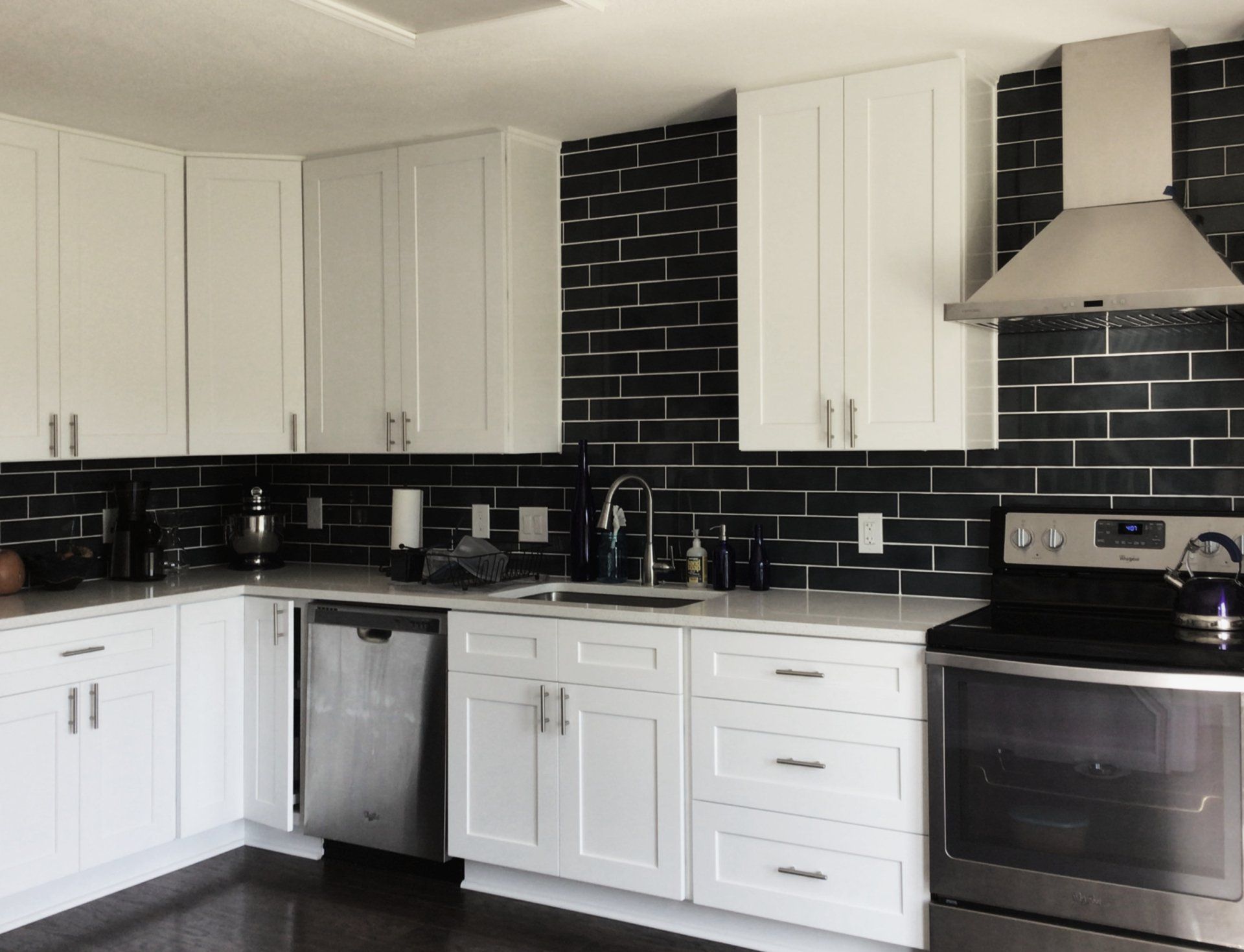 A kitchen with white cabinets and black brick walls