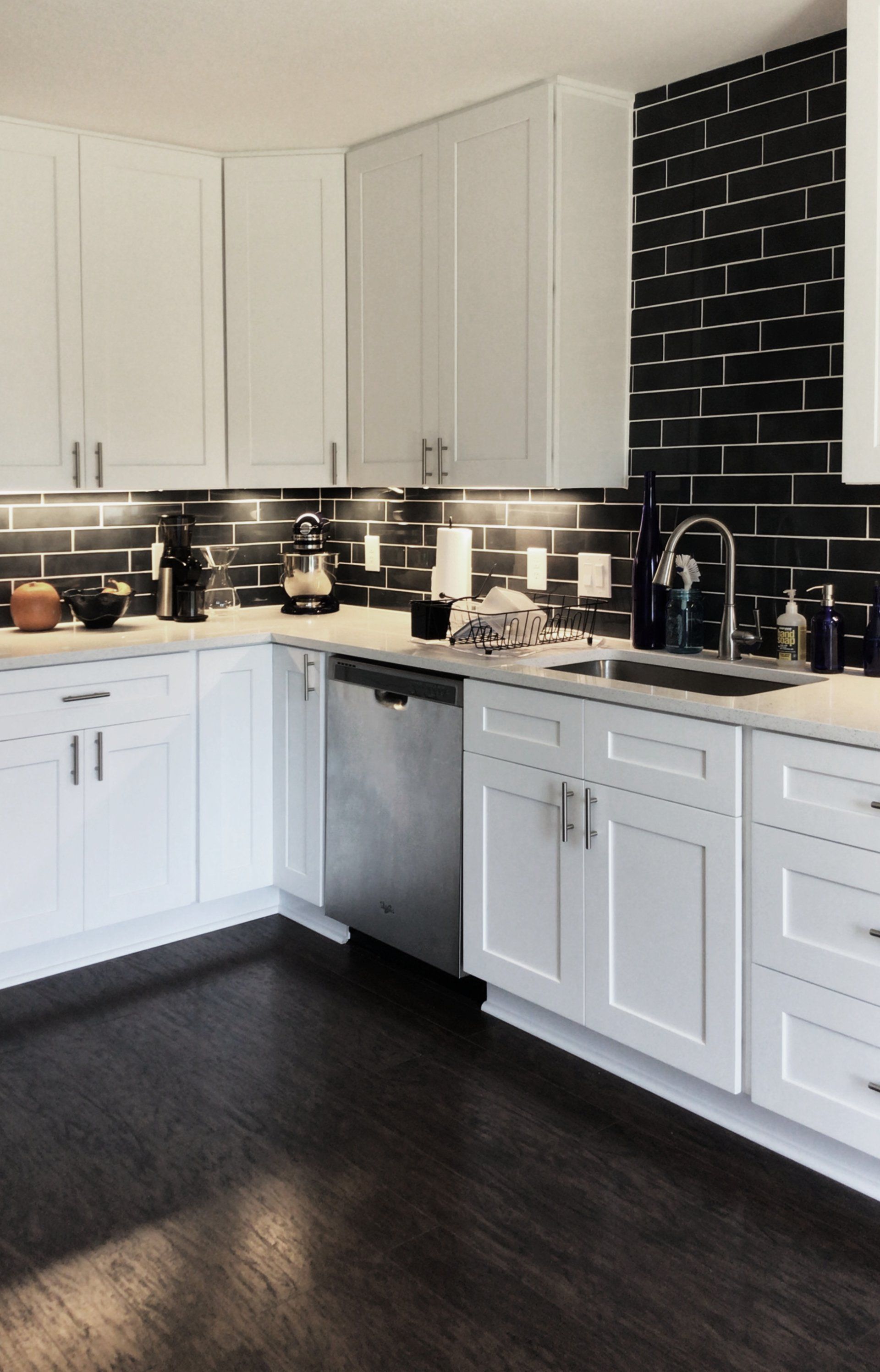 A kitchen with white cabinets and a stainless steel dishwasher