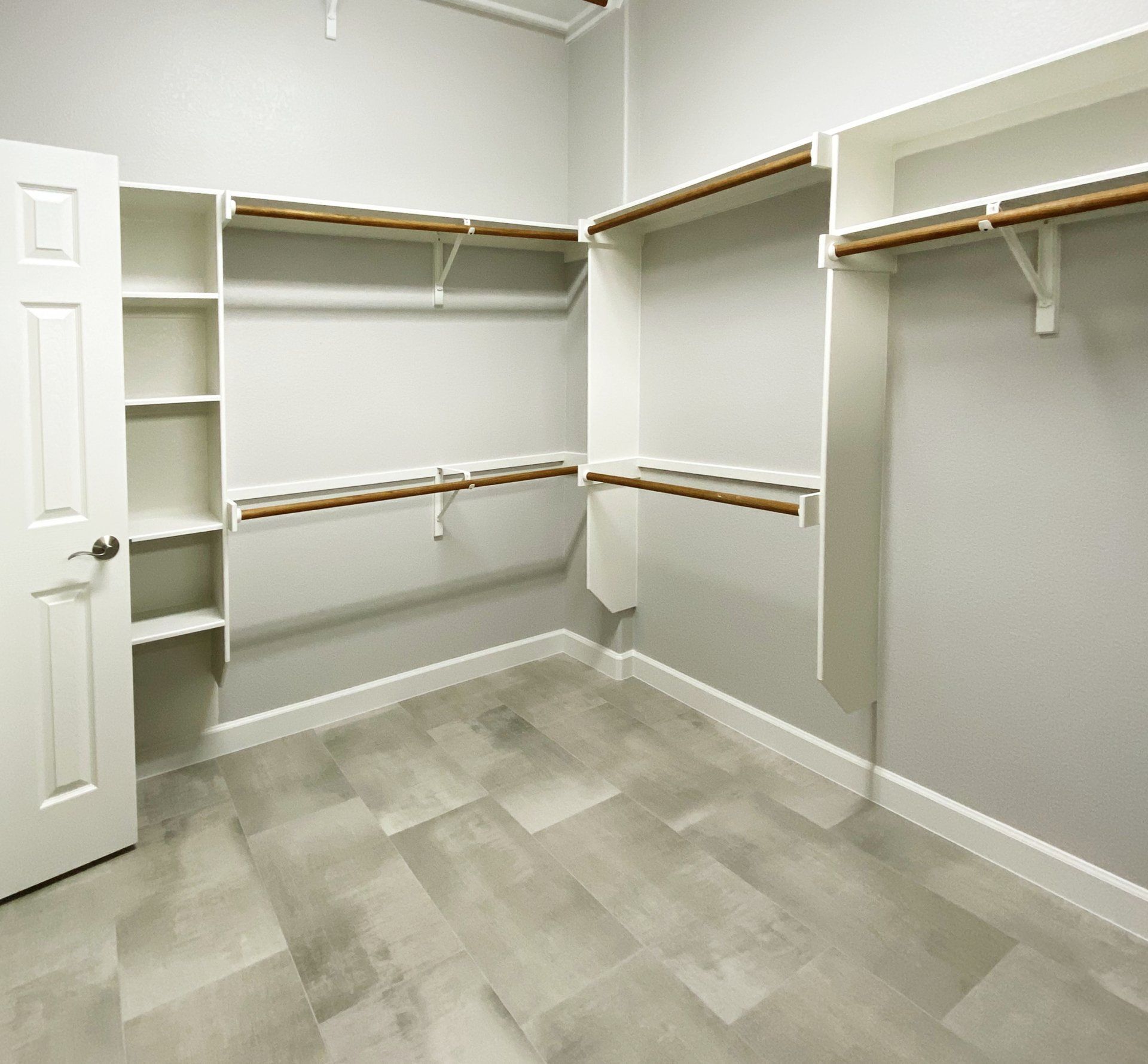 An empty walk in closet with a tiled floor and shelves.