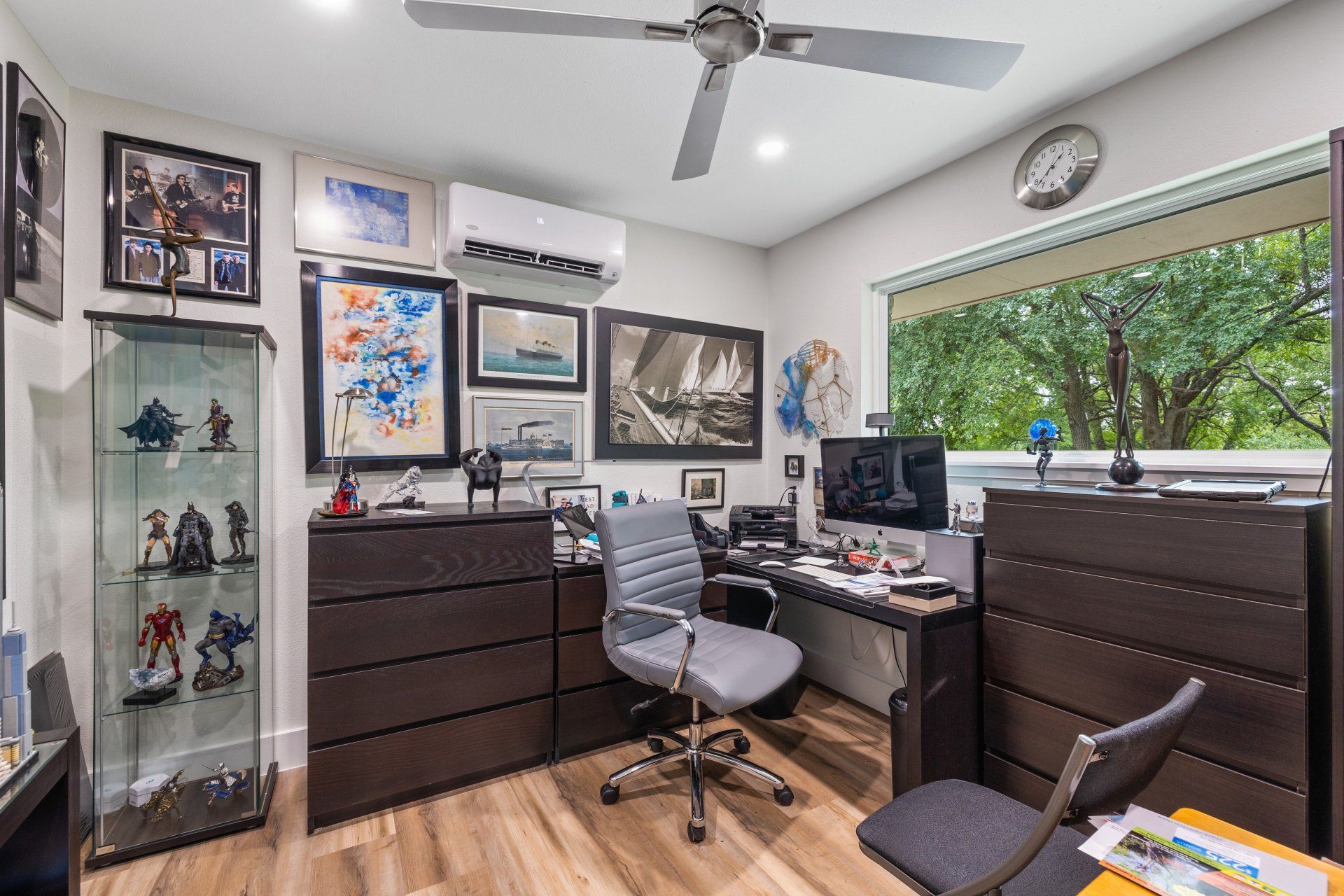 A home office with a desk , chair , dresser and a ceiling fan.