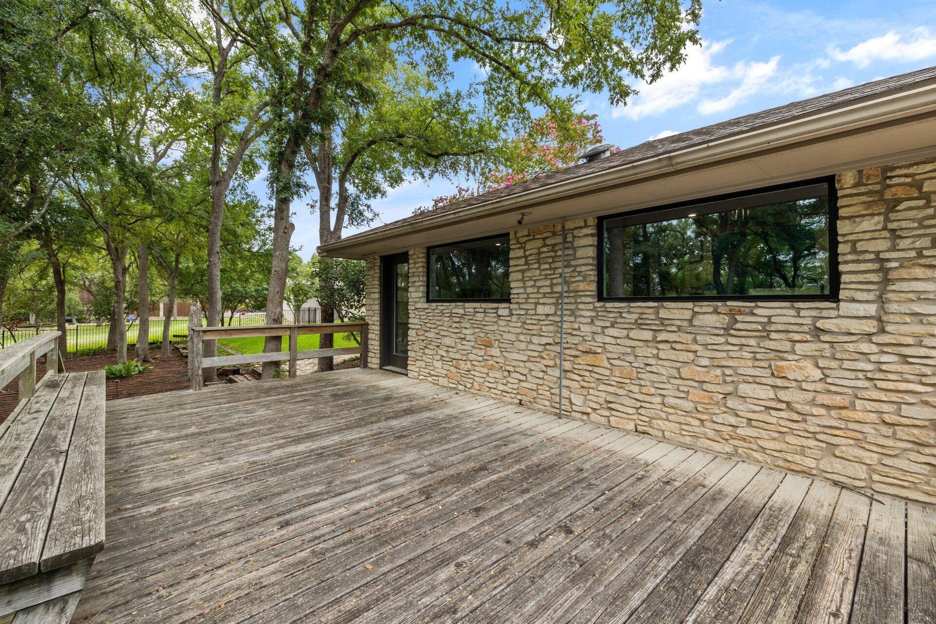There is a wooden deck in front of a stone building.