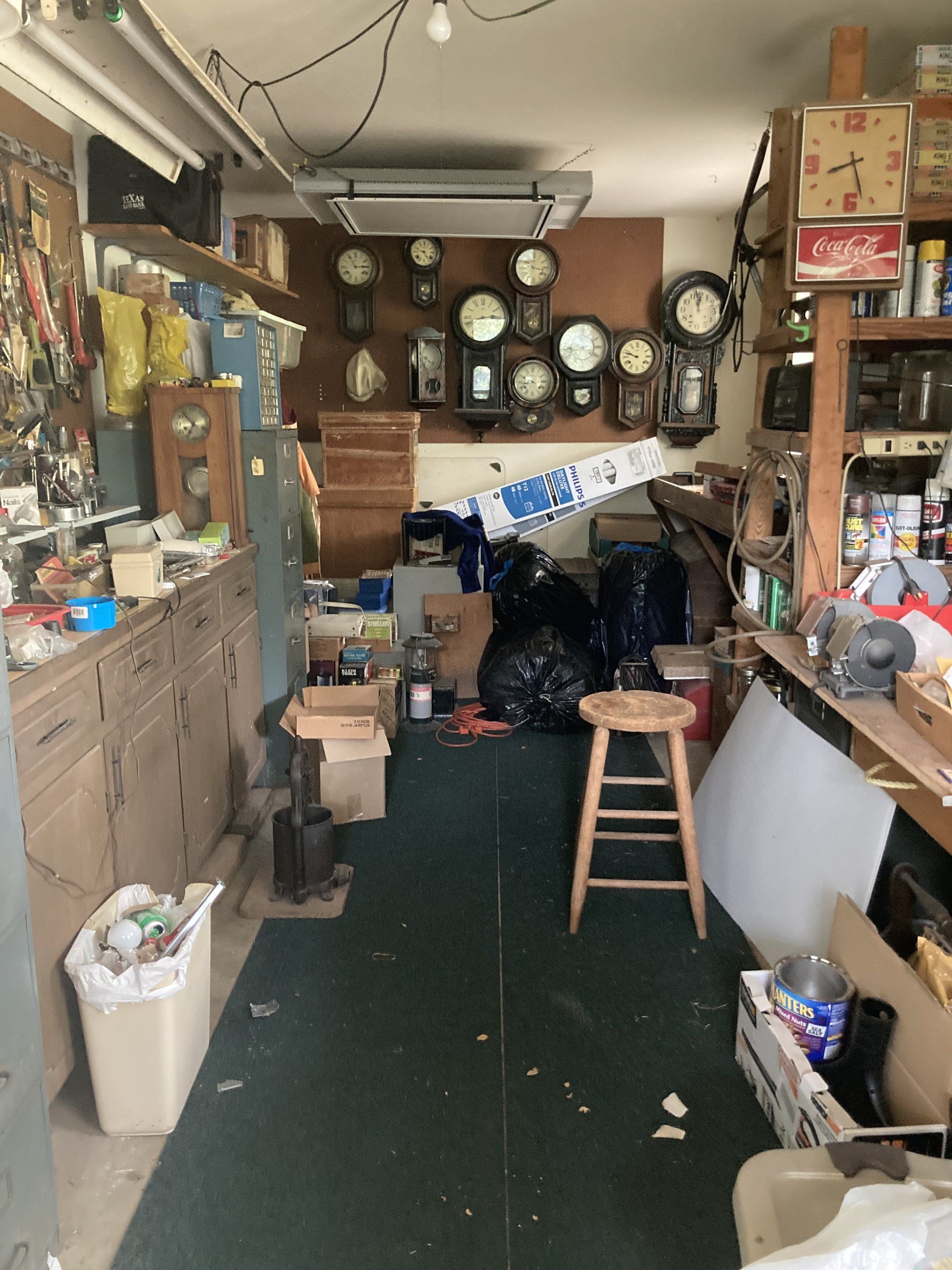 A messy room with clocks on the wall and a stool