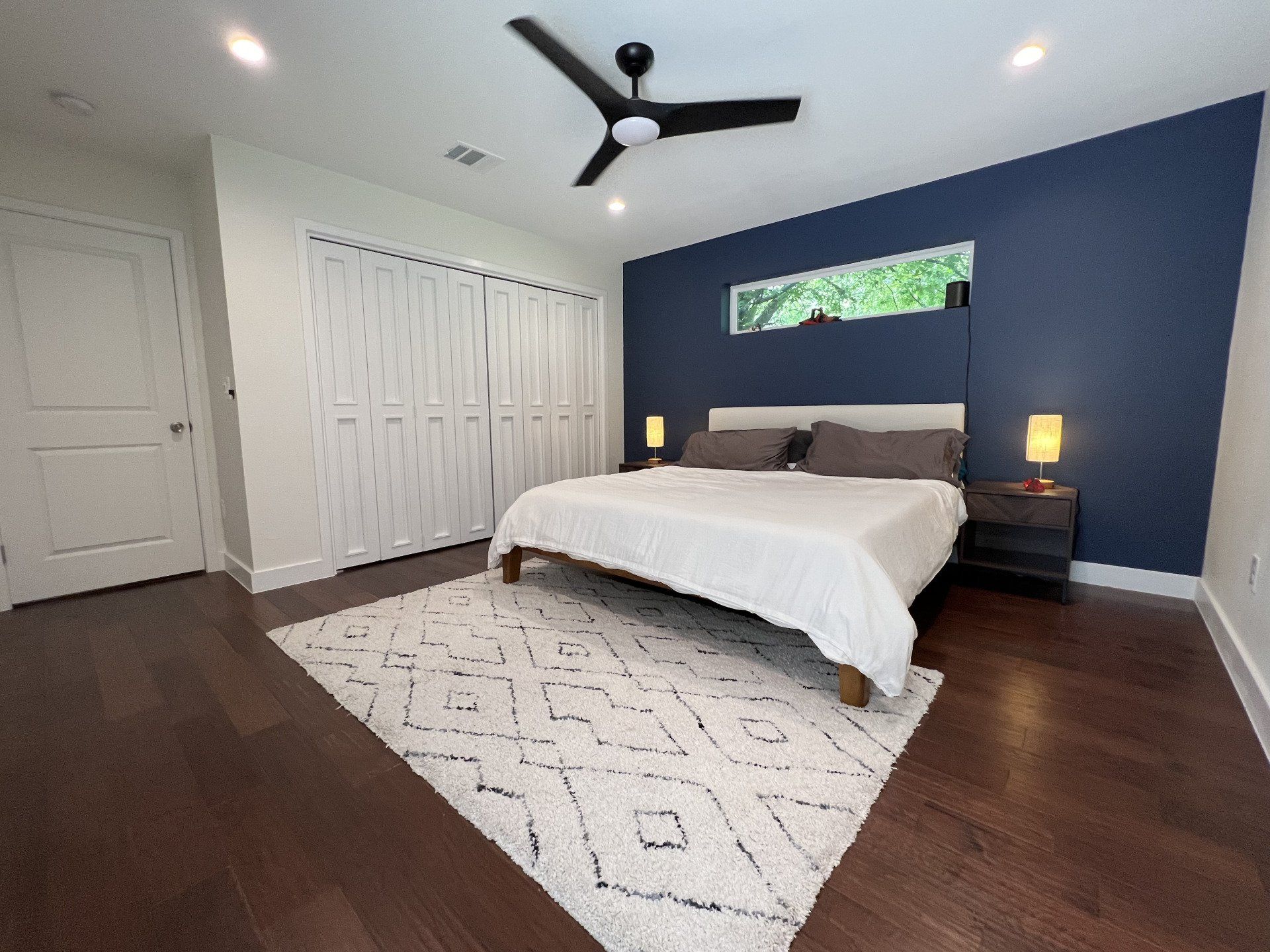 A bedroom with a ceiling fan and a bed.