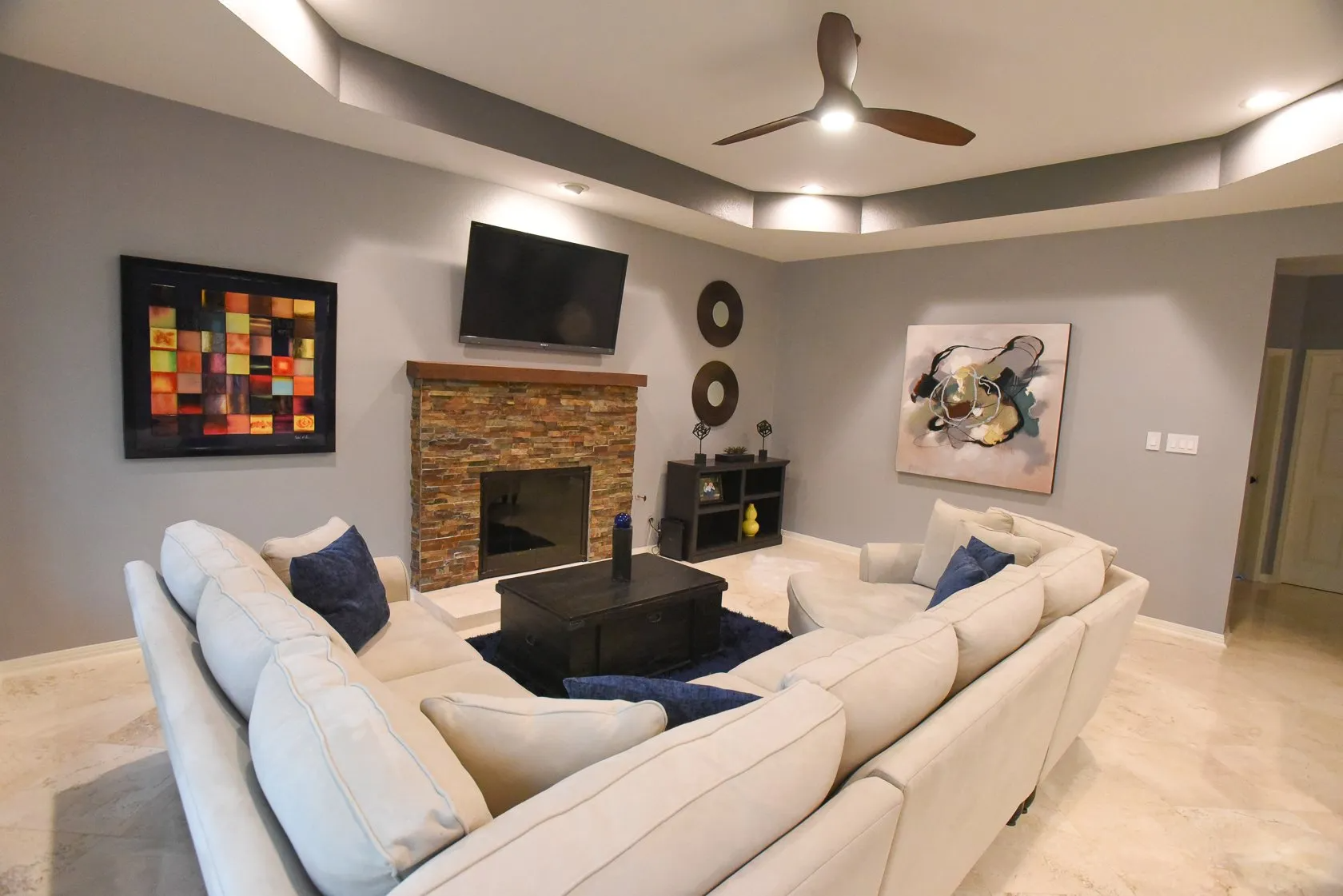 A living room with a couch , fireplace , television and ceiling fan.