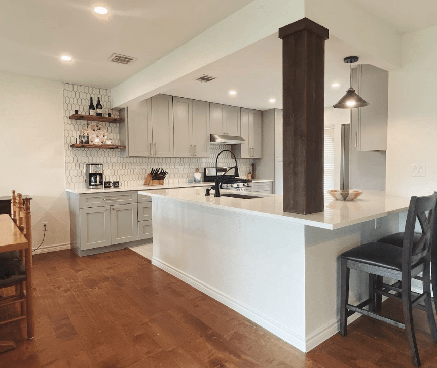 A kitchen with white cabinets , a sink , a table and chairs.