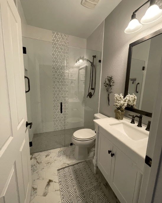 A bathroom with a toilet , sink , mirror and shower.