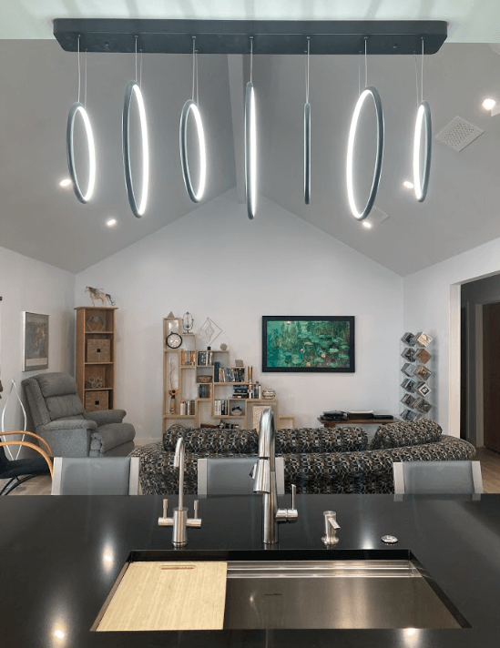 A kitchen with a sink and a living room in the background