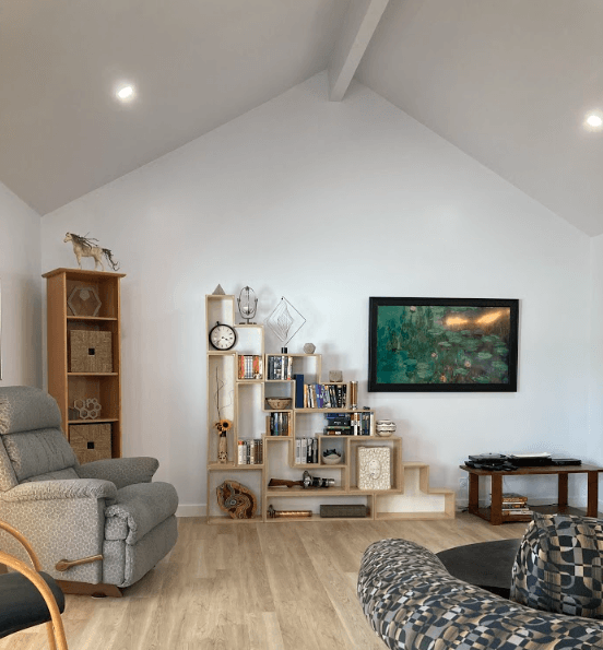 A living room with a vaulted ceiling and a picture on the wall