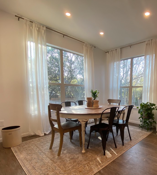 A dining room with a table and chairs in front of a window