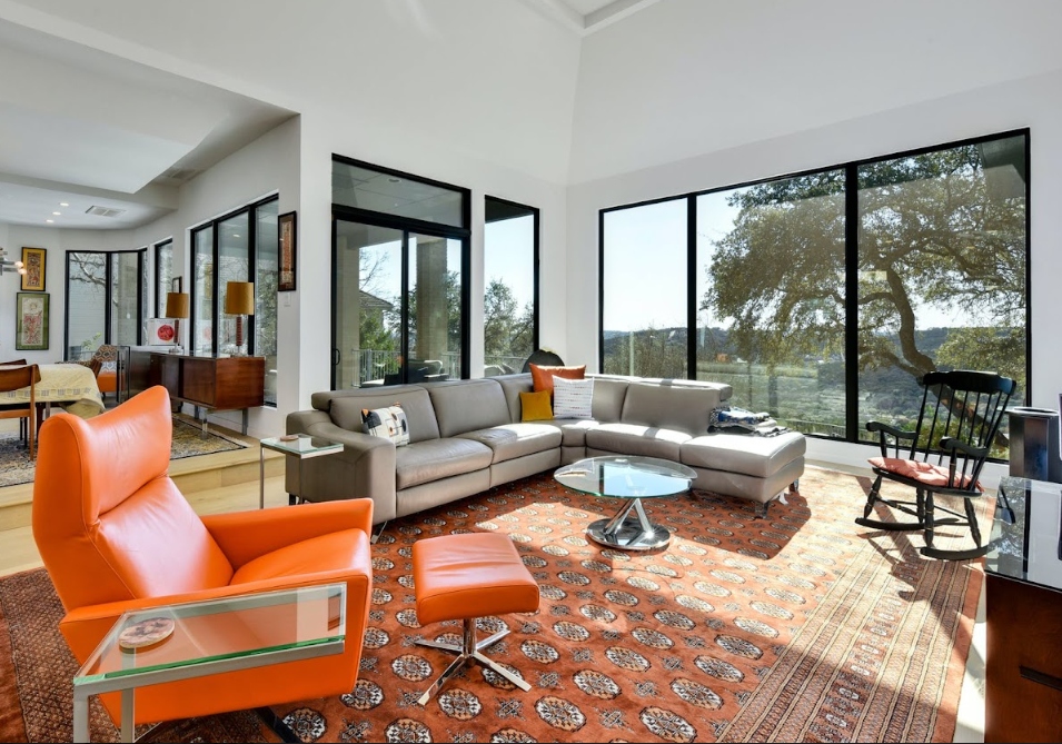 A living room with a couch , chair , ottoman and table