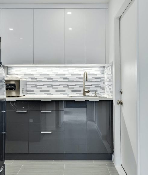 A kitchen with gray cabinets and white counter tops