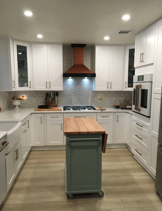 A kitchen with white cabinets , stainless steel appliances , and a wooden island.