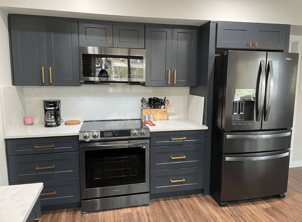 A kitchen with stainless steel appliances and gray cabinets.