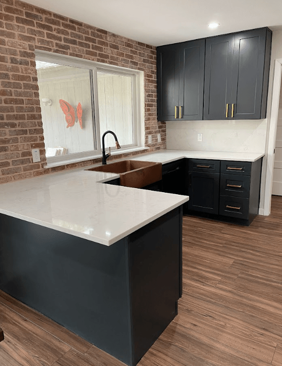 A kitchen with black cabinets , a sink , and a window.