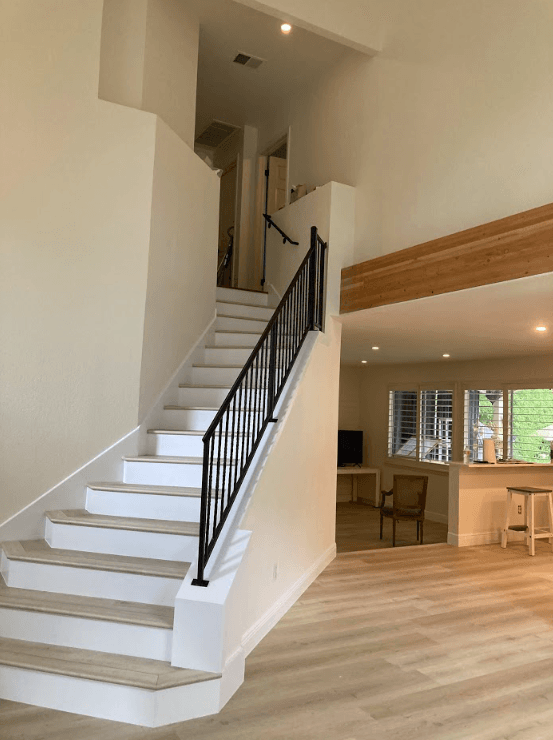 A white staircase with a black railing is leading up to the second floor of a house.