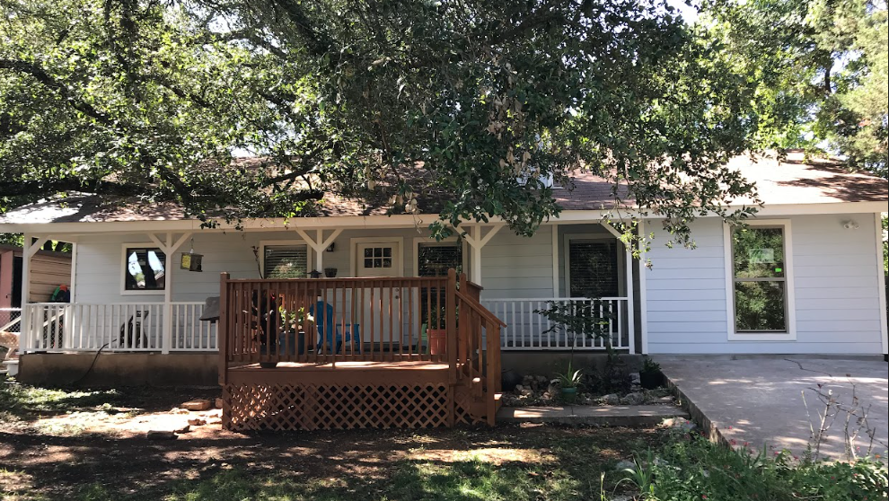 A white house with a large porch and a wooden deck.