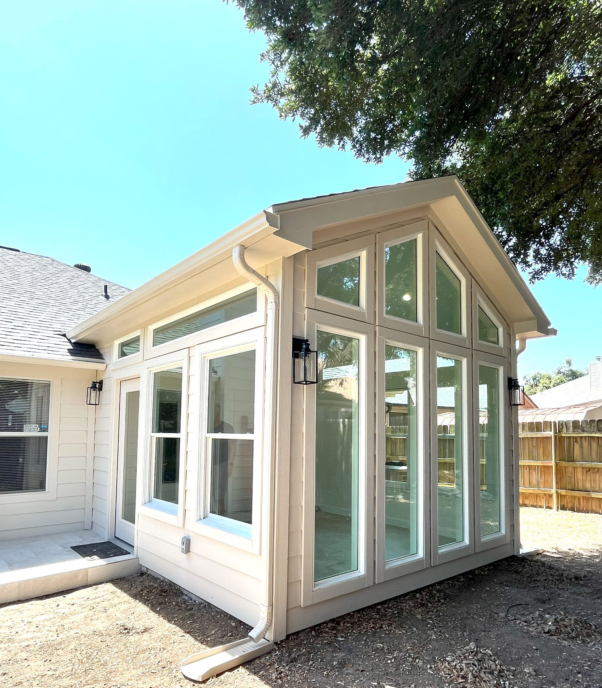 A white house with a large sunroom with a lot of windows.