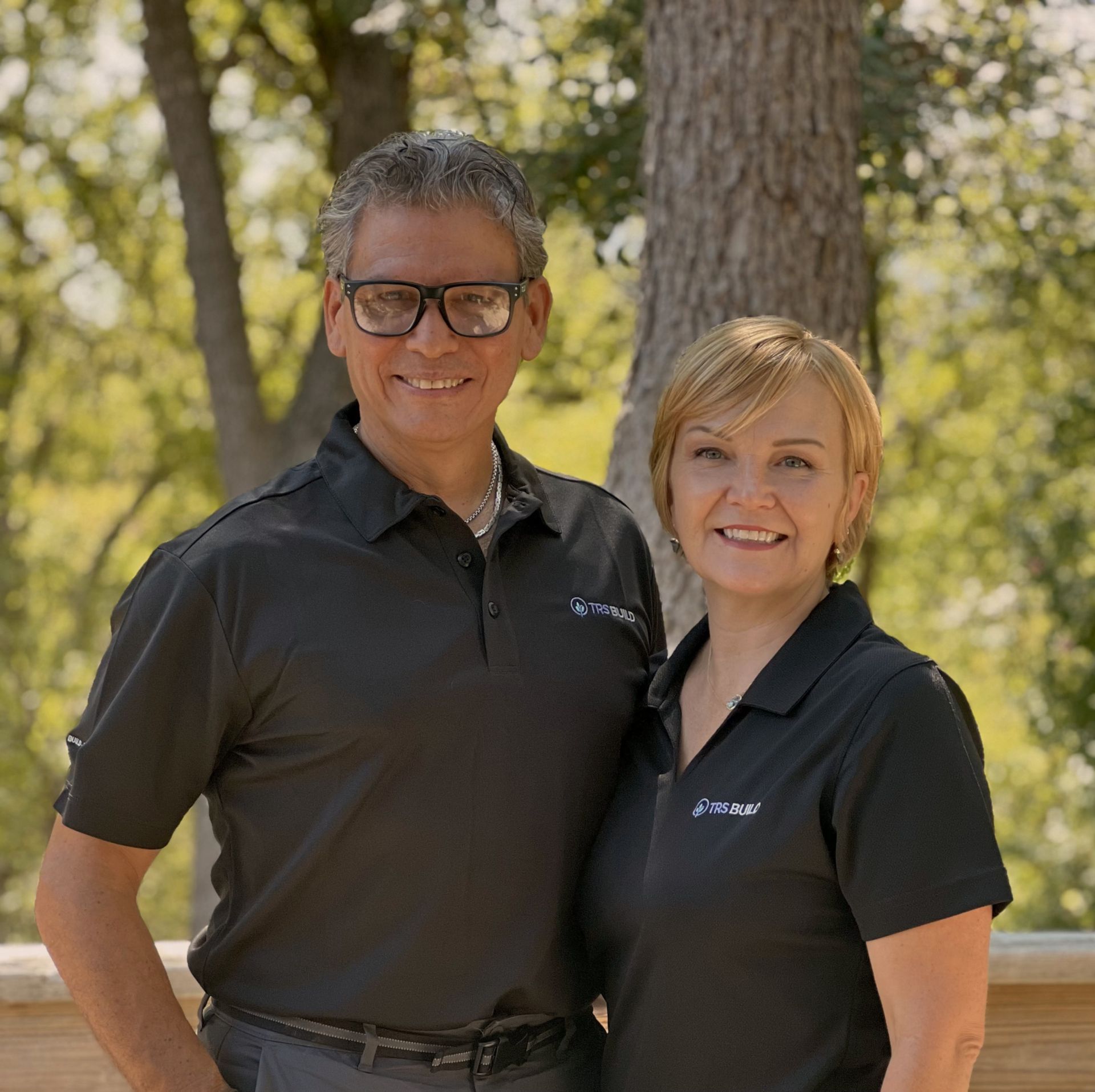 A man and a woman are posing for a picture in front of a tree.