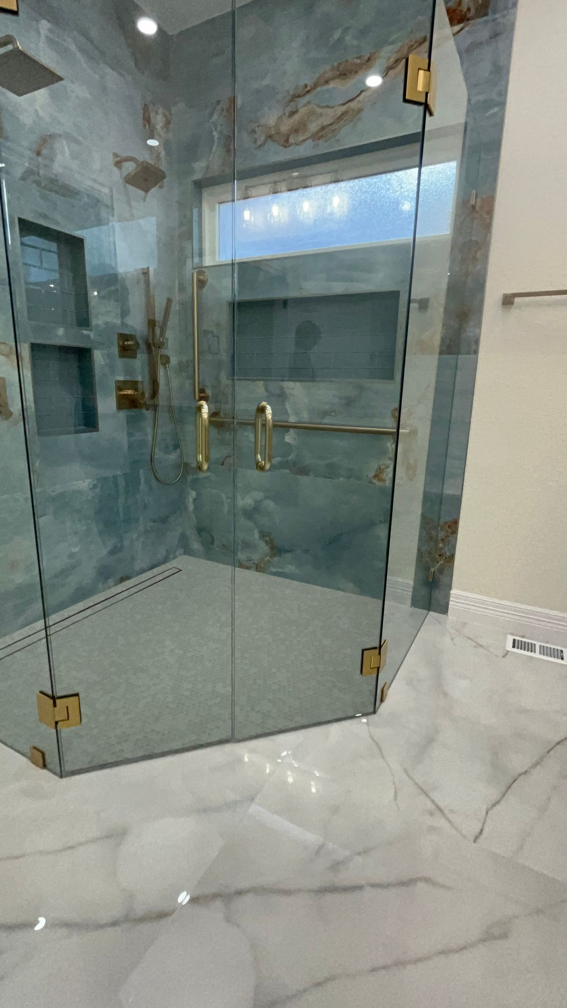 A bathroom with a walk in shower with a glass door.