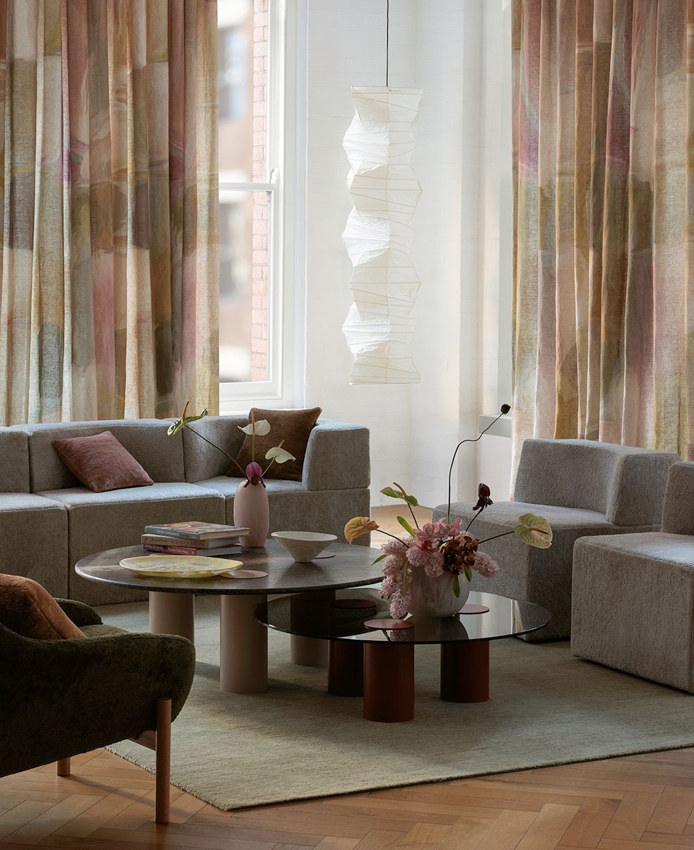 Living room with modular sofa, glass coffee tables, and patterned curtains.