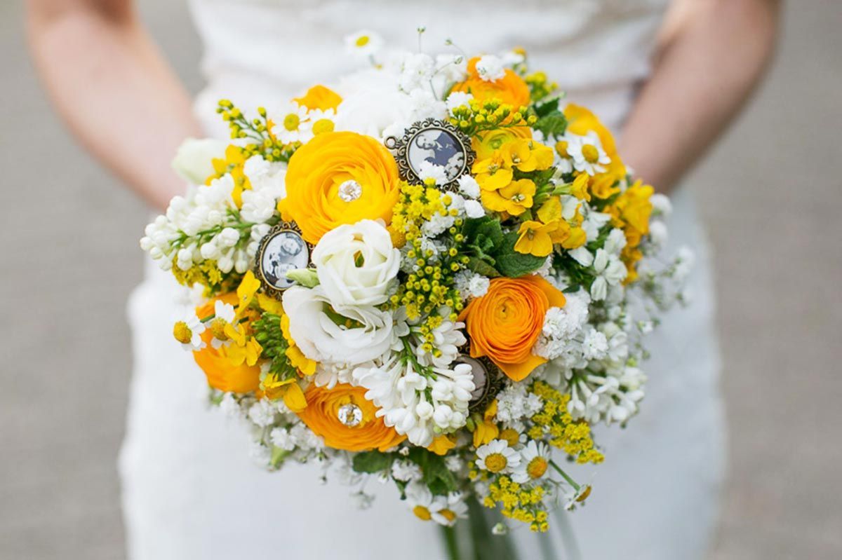 Eine Braut in einem weißen Kleid hält einen Strauß aus gelben und weißen Blumen.