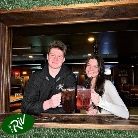 A man and a woman are holding beer mugs in front of a window.