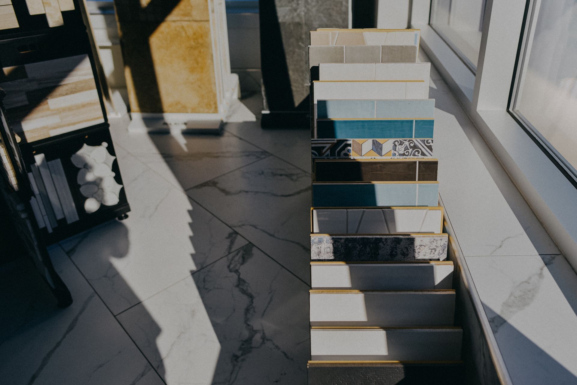 Sample tiles in various colors and patterns displayed on a showroom stand.