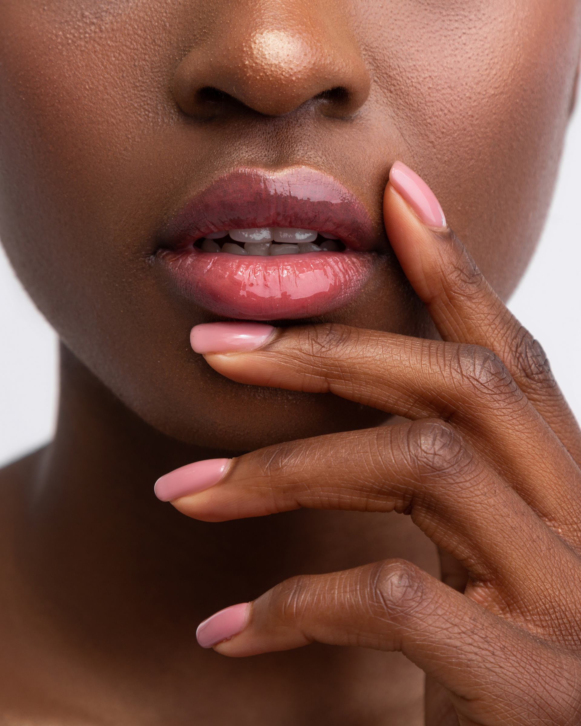 A close up of a woman 's face with pink nails and pink lips.