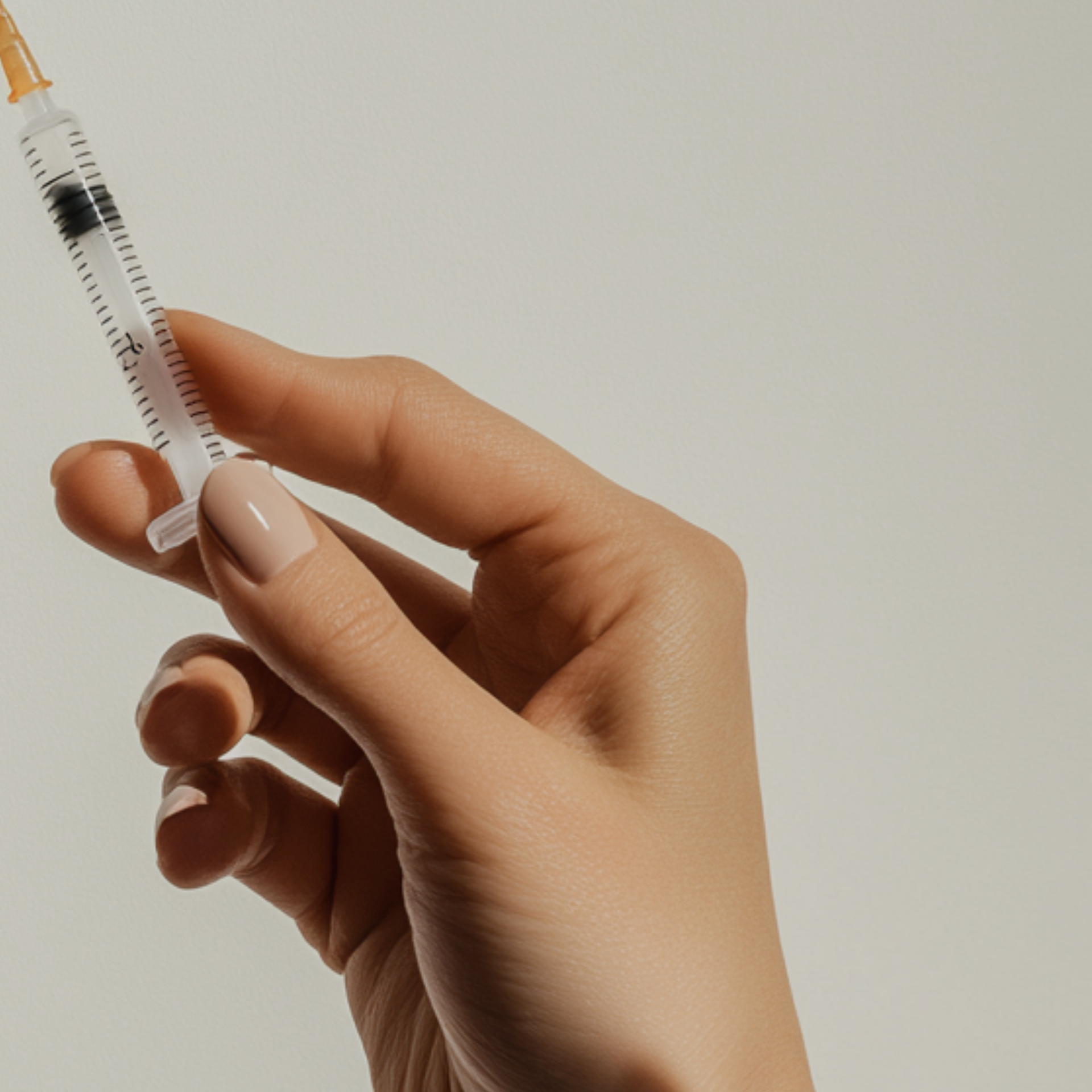 A woman 's hand holds a syringe with a needle in it