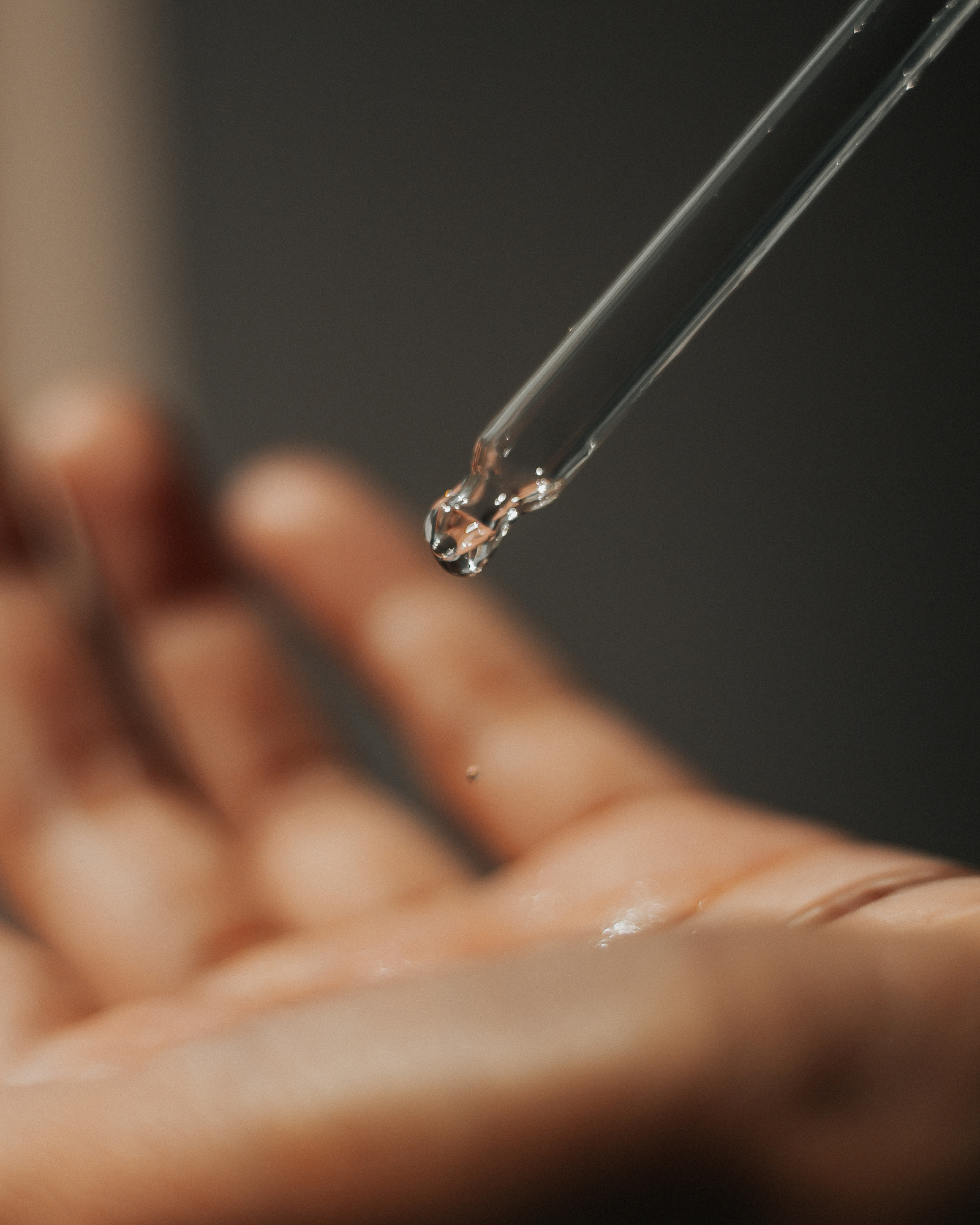 A drop of liquid is being poured from a pipette into a person 's hand.