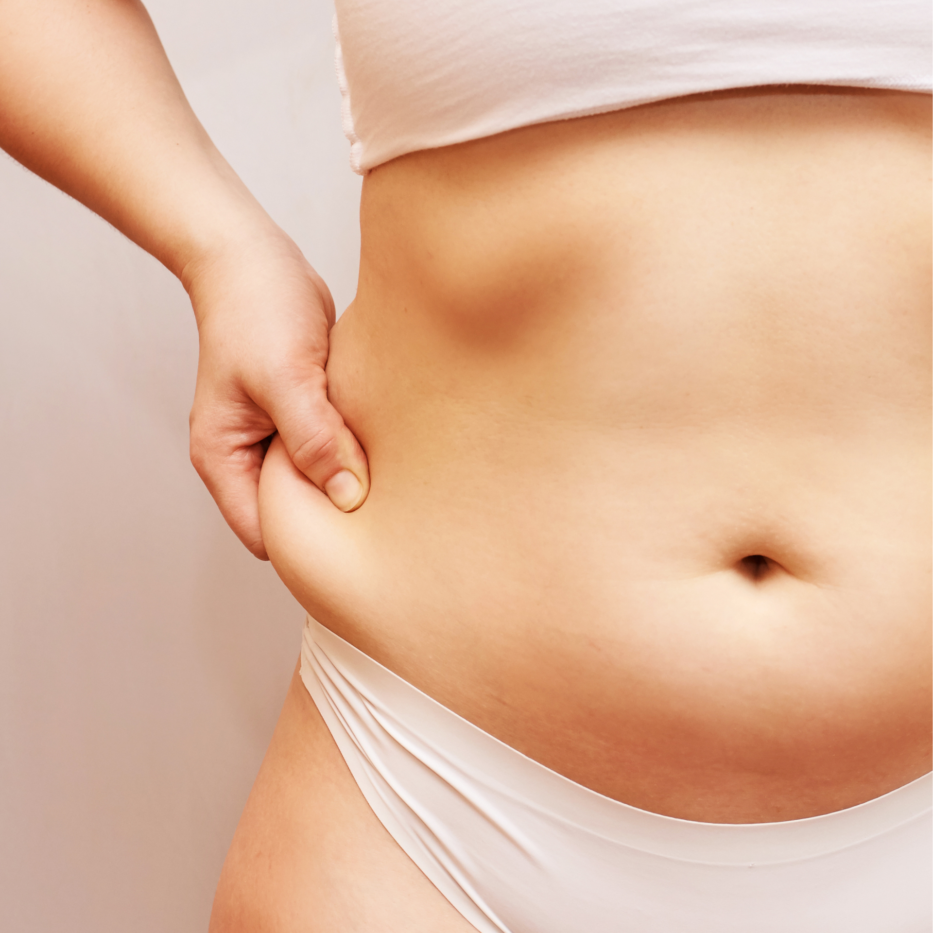 A woman in white underwear is holding her stomach with her hand