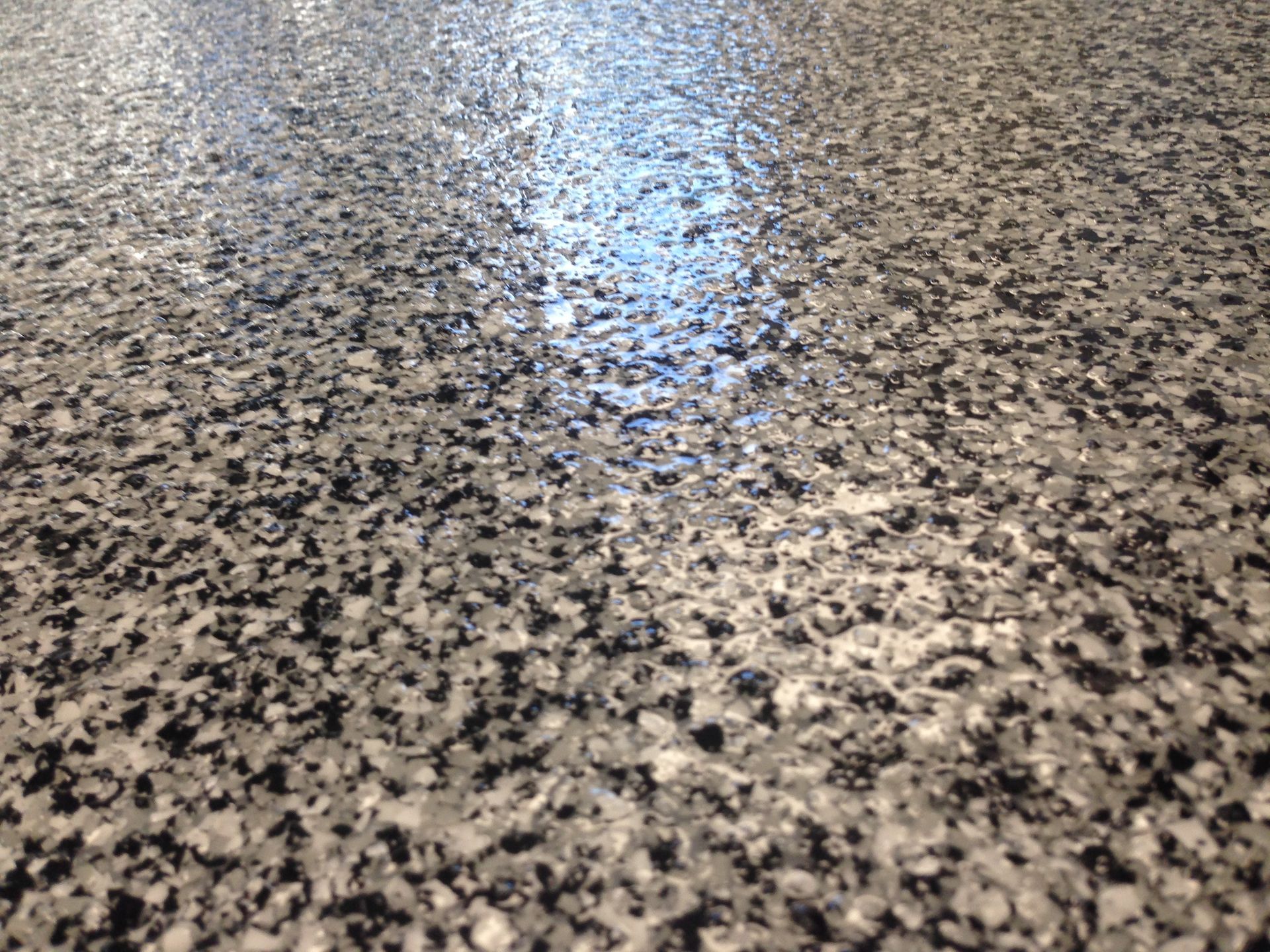 Gros plan sur un sol gris et noir brillant, moucheté et à l'aspect réfléchissant.