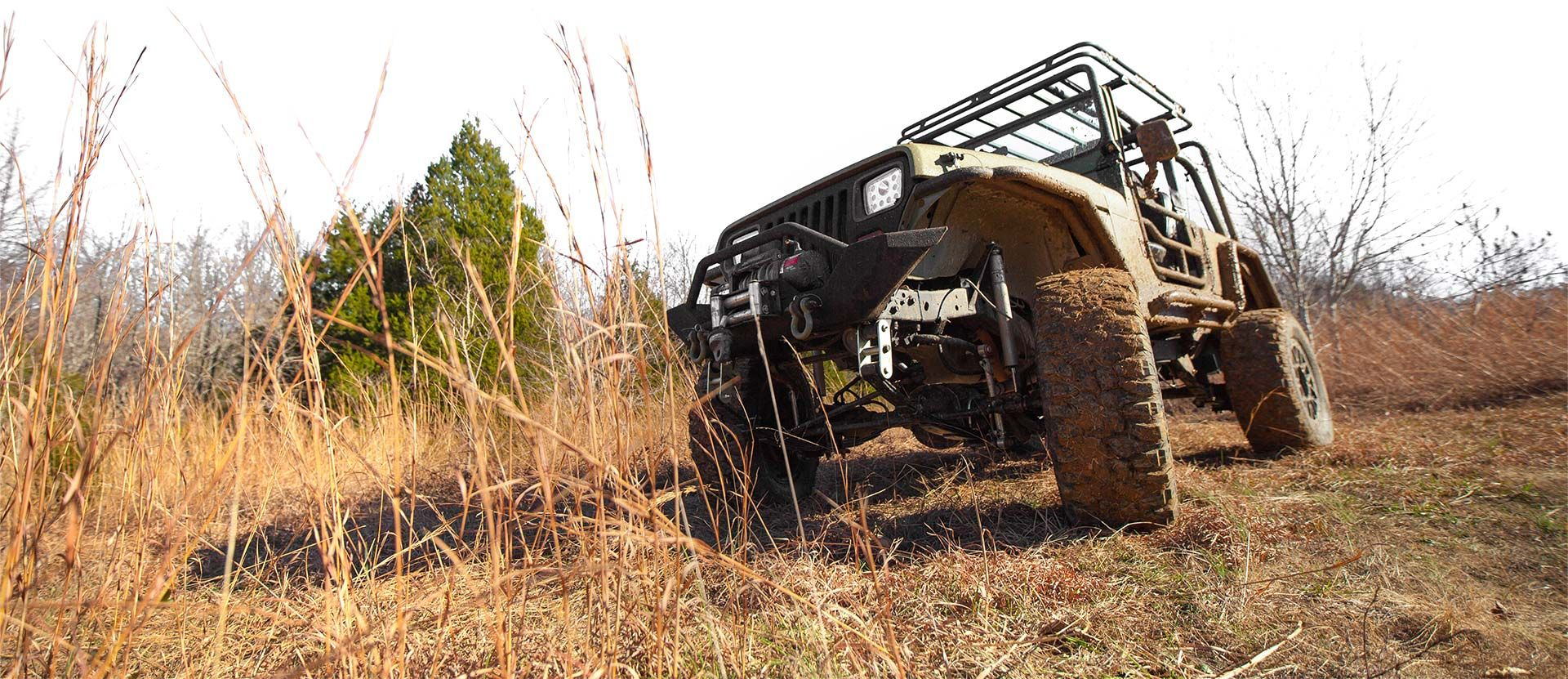 Véhicule tout-terrain en montée à travers de hautes herbes sèches.