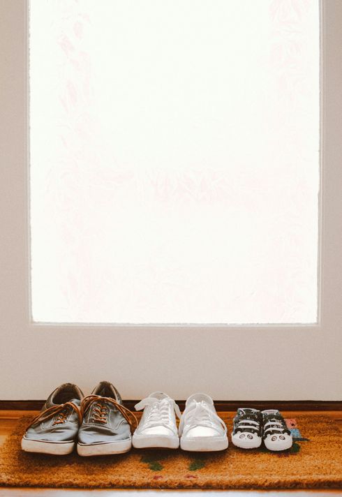 Three pairs of shoes are sitting on a door mat.