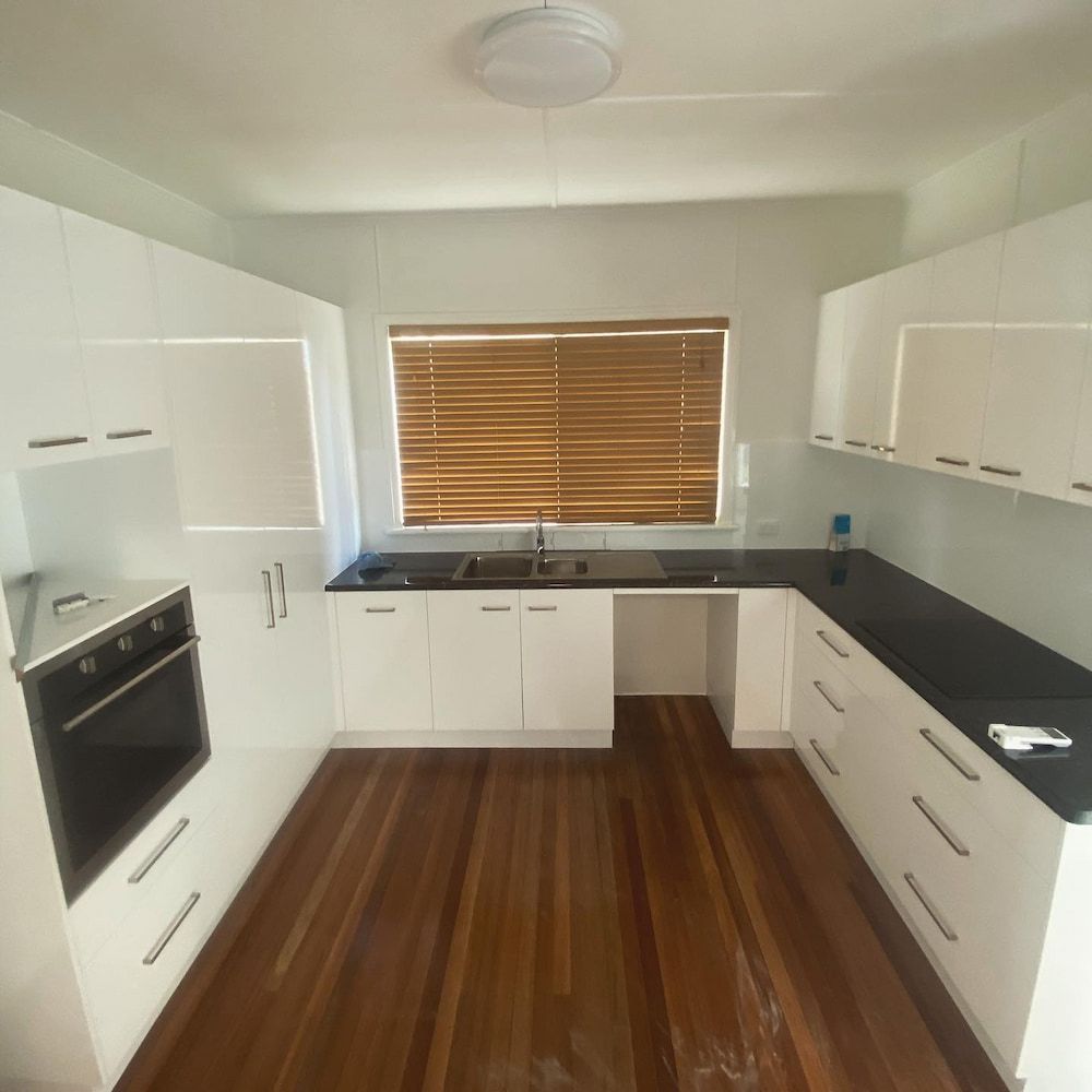 A Kitchen With White Cabinets and Black Counter Tops — CJM Plumbing & Roofing Mackay in Mackay, QLD
