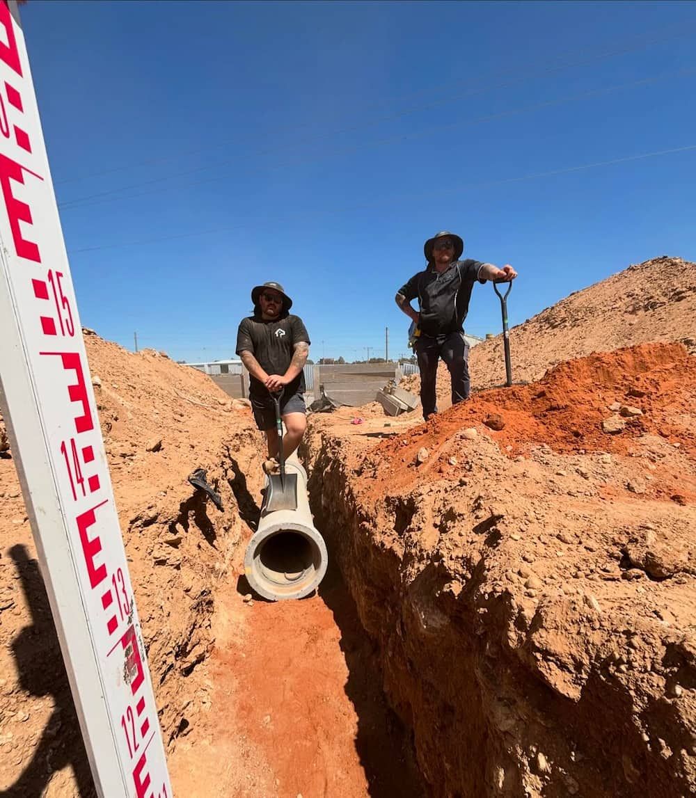 Two Men Are Standing in a Trench Next to a Measuring Stick New Roofs — CJM Plumbing & Roofing Mackay in Mackay, QLD