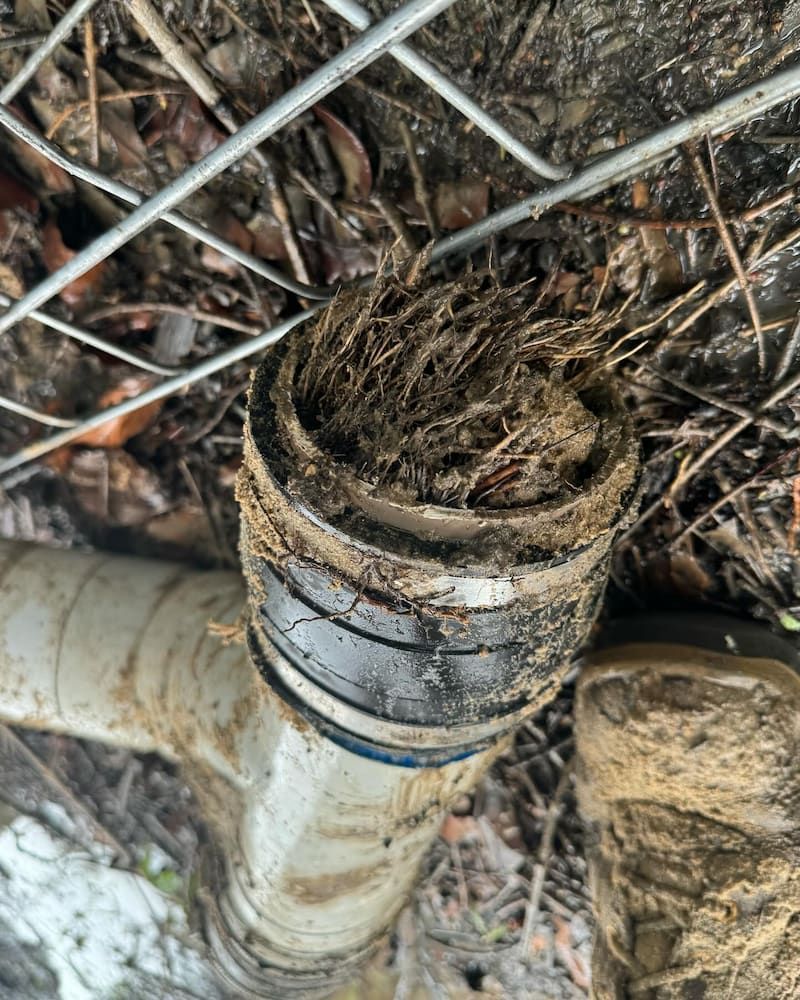 A Dirty Pipe is Sitting on the Ground Next to a Wire Fence — CJM Plumbing & Roofing Mackay in Mackay, QLD