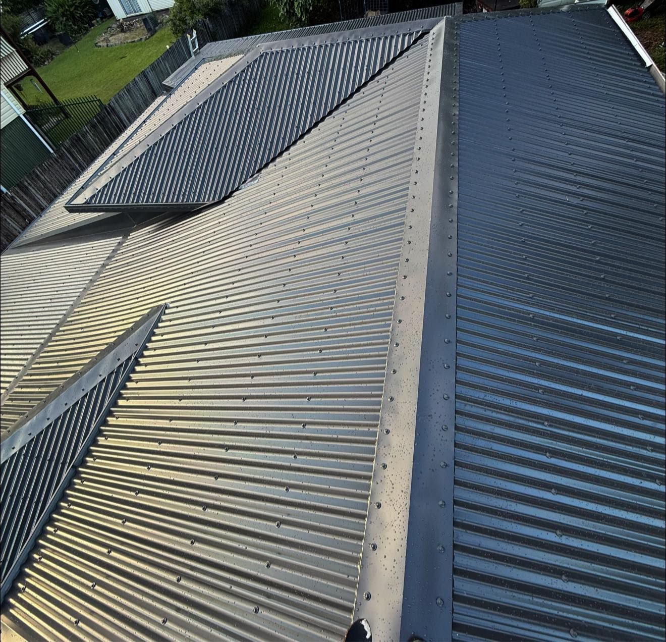 A Person is Standing on Top of a Green Roof — CJM Plumbing & Roofing Mackay in Mackay, QLD