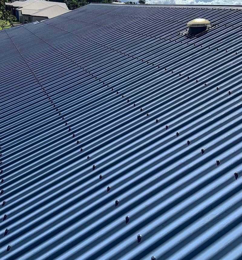 A Blue Corrugated Metal Roof With a Vent on Top of It — CJM Plumbing & Roofing Mackay in Mackay, QLD